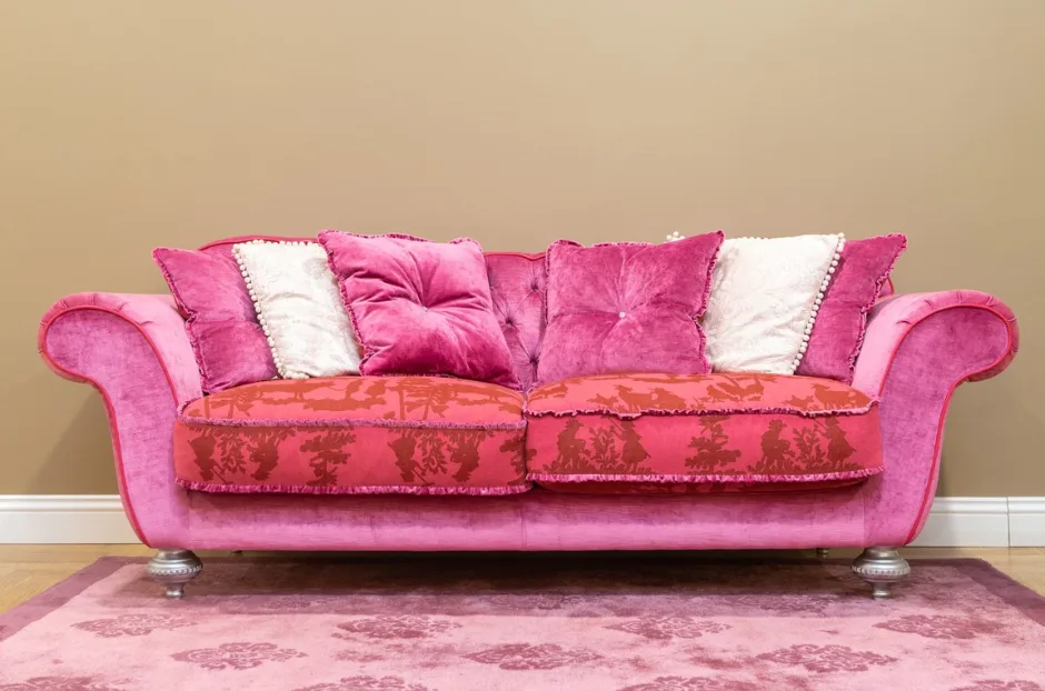 Elegant pink velvet sofa with plush pillows against a brown background