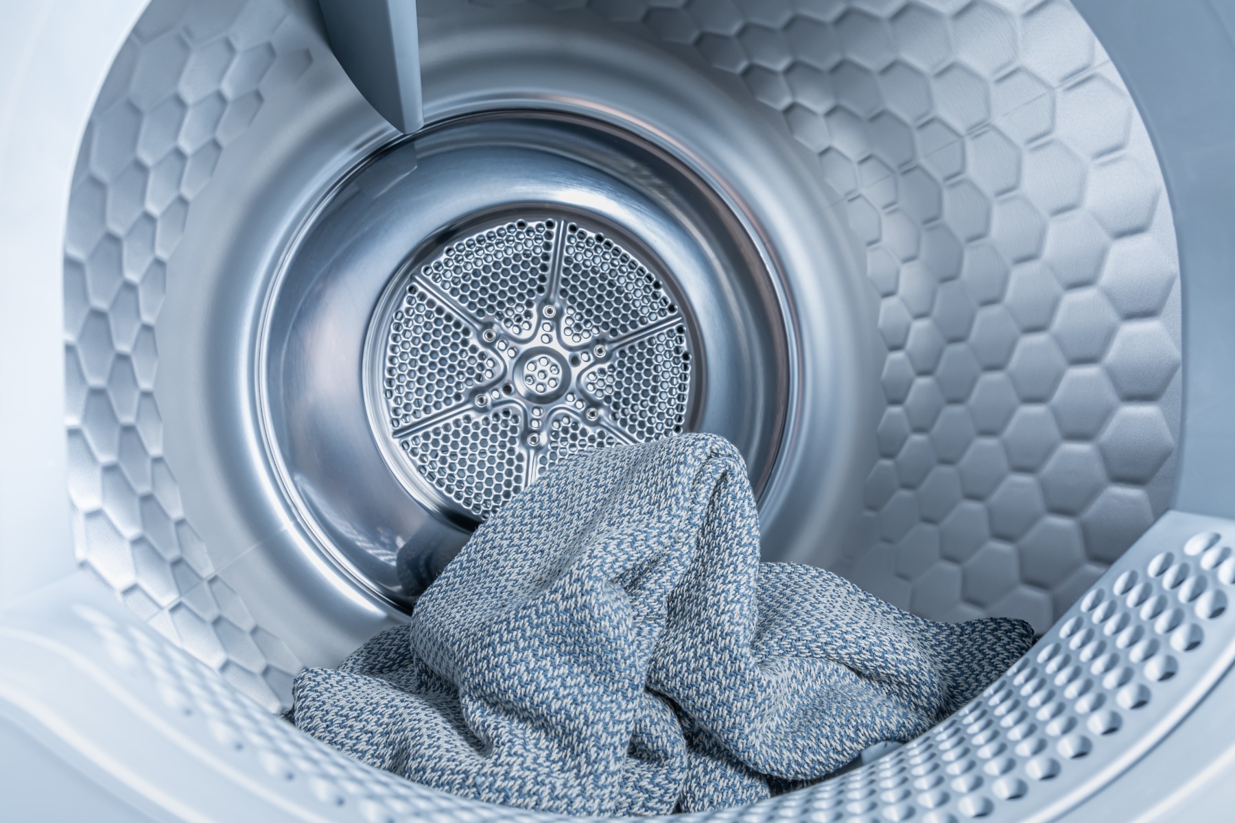 Front-load clothes dryer with the door open and clean laundry inside
