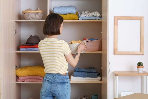 A woman placing a basket of clothes into her closet