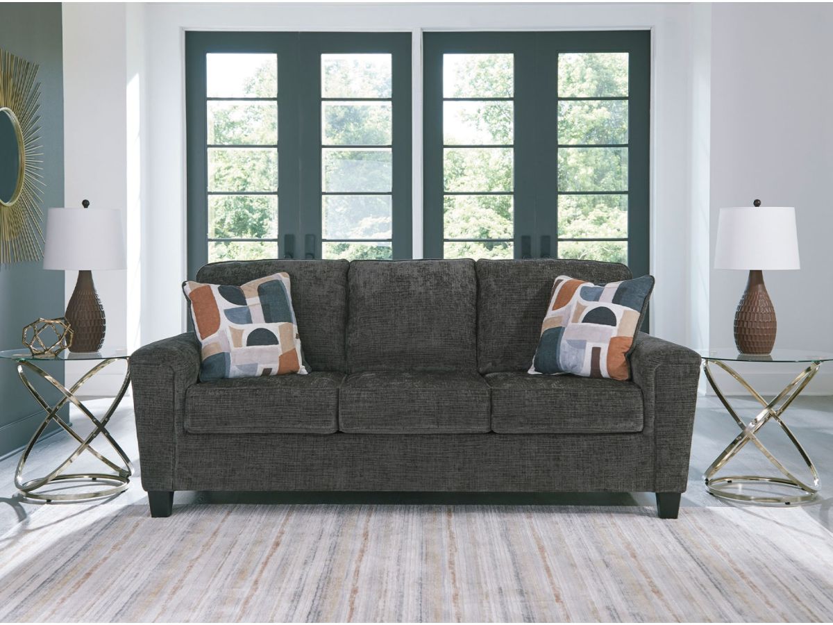 A grey couch with blue pillows in front of a window