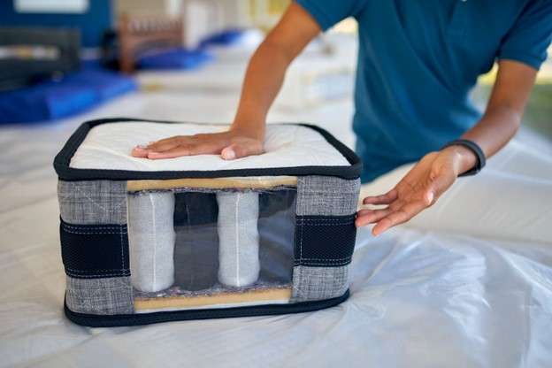 Person showcasing a pocket spring mattress sample