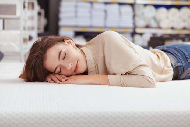 Woman lying on top of a foam mattress in a mattress store