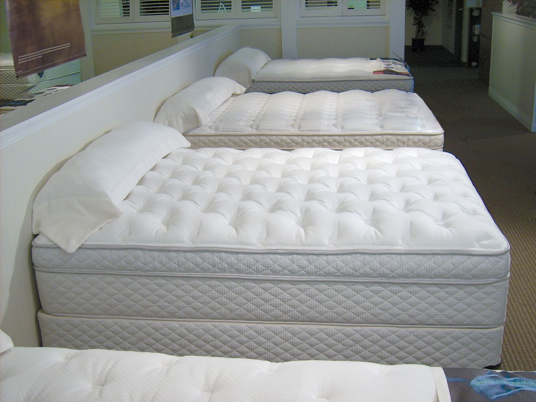 A row of mattresses in a Surplus Furniture showroom
