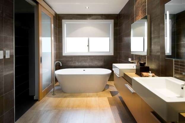 A sleek spa-like bathroom with wood floors and white fixtures