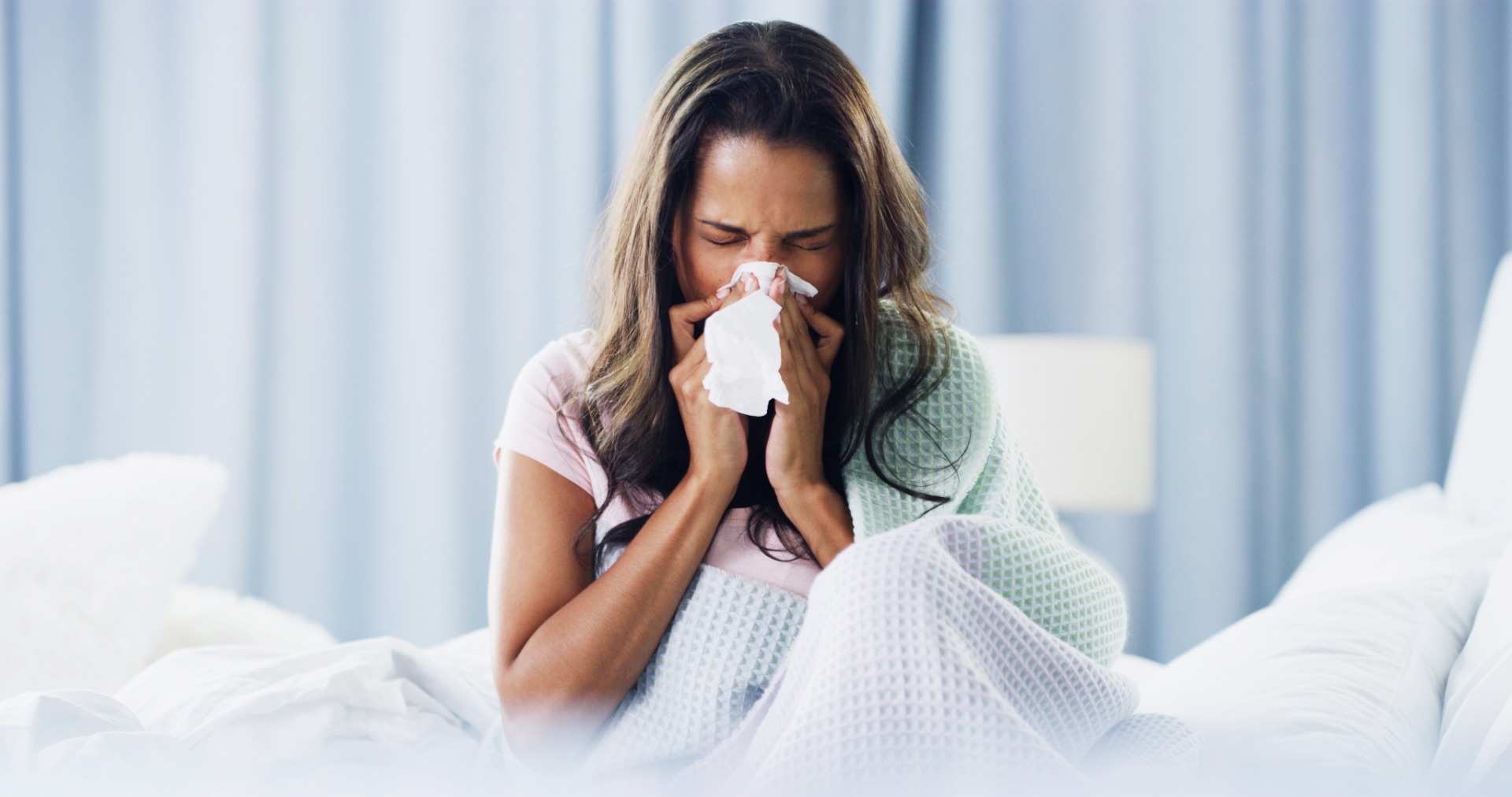Woman sneezing in bed