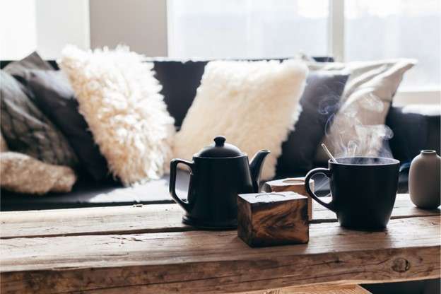 A couch with several fuzzy cushions lending a cozy feel to a cabin living room