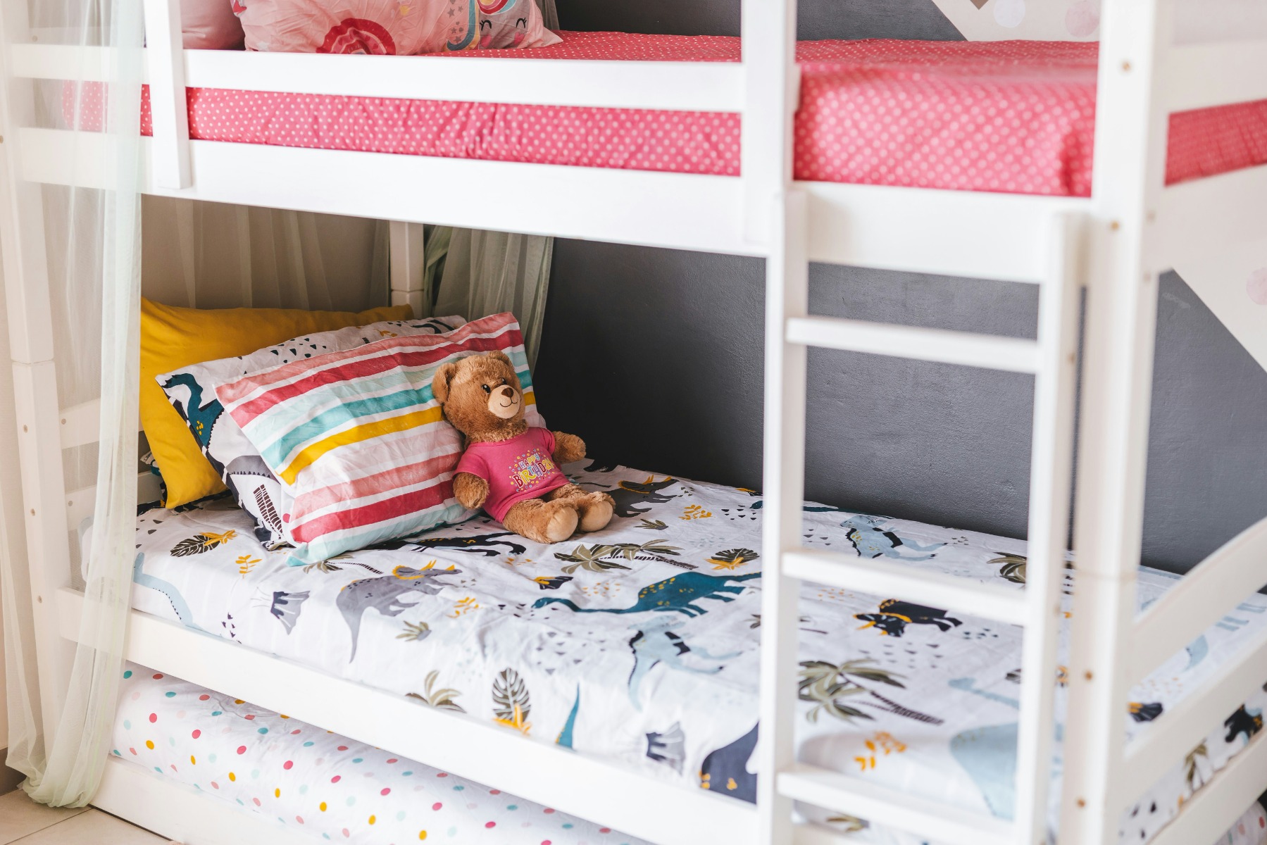 White bunk bed and pull-out with colourful sheets in a child’s room