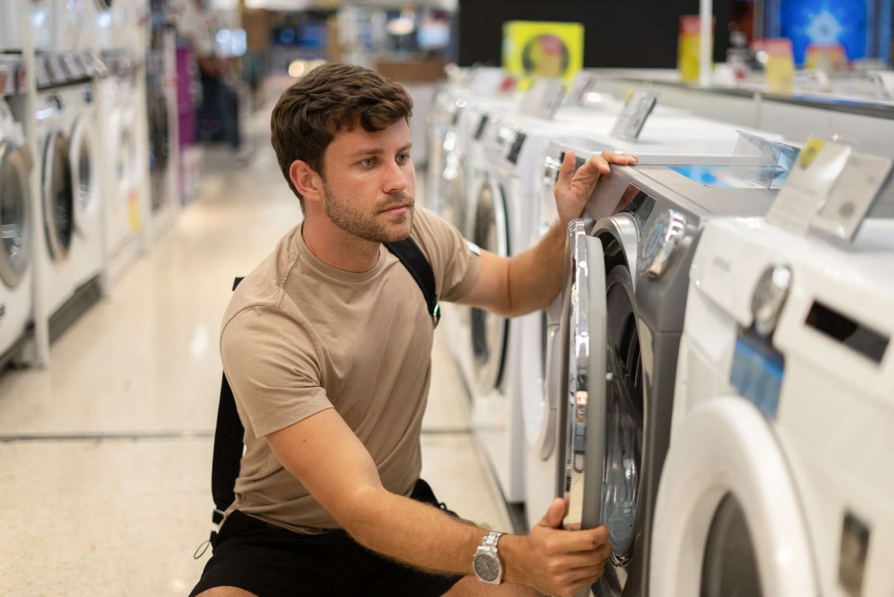 A young man checking out washing machines in-store