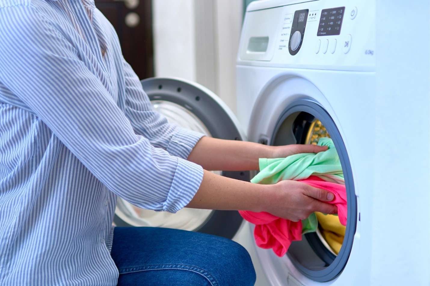 Someone loading laundry into a front-load washing machine