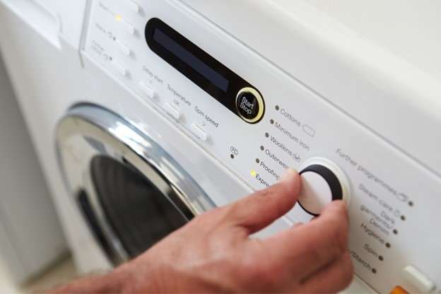 A hand adjusting the cycle settings on a washing machine