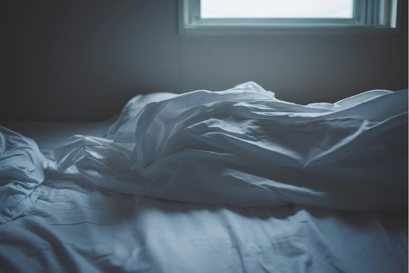 Sheets and comforter crumpled on a bed